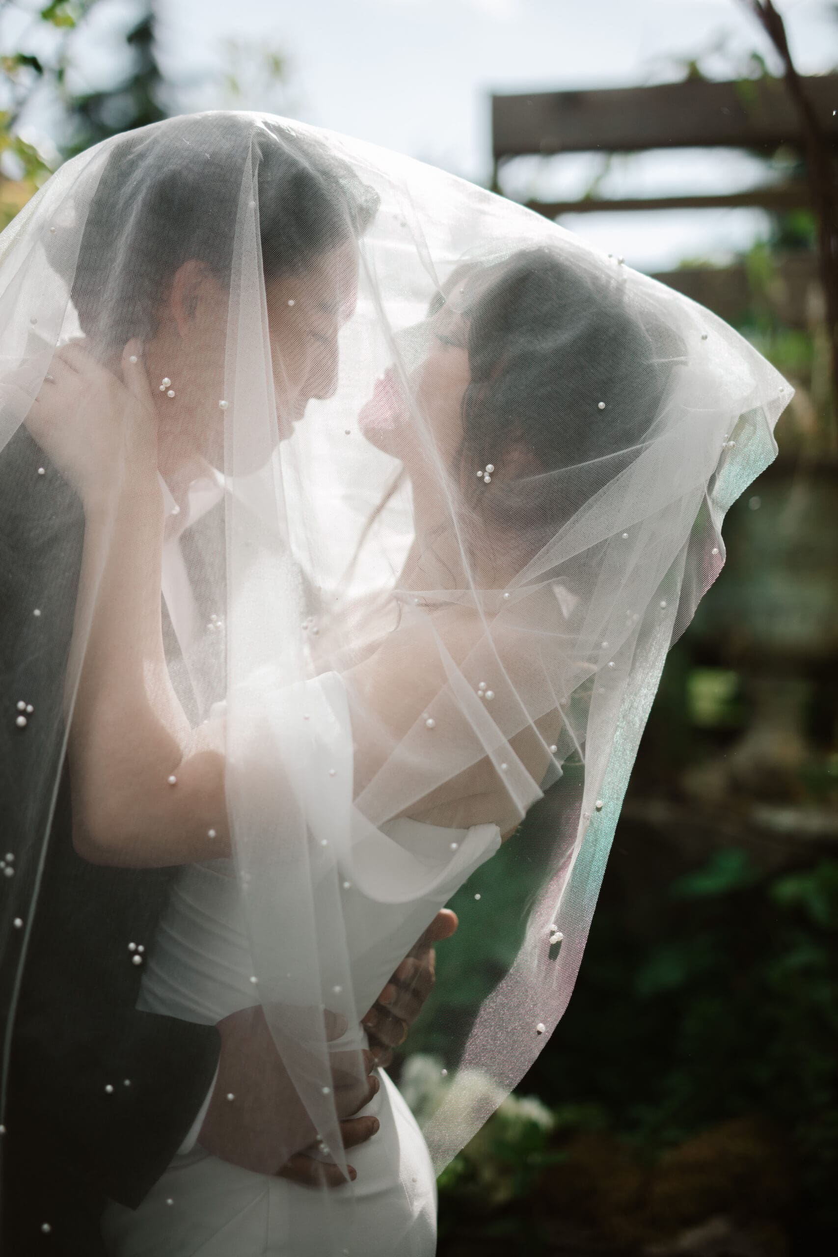Intimate moment as a couple embraces under a soft, pearl-dotted veil—an ethereal capture by a Washington wedding photographer.