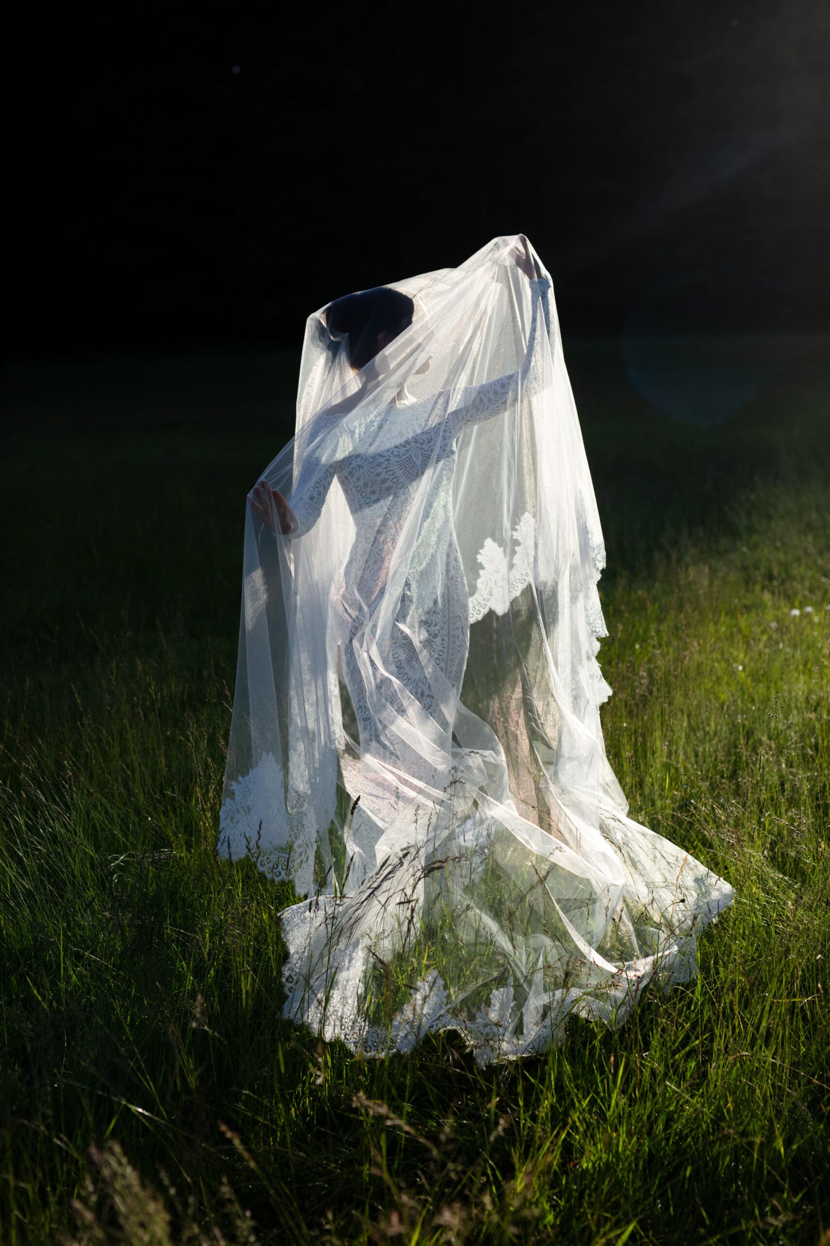 A bride enveloped in a flowing veil moves gracefully through a sunlit meadow, captured by a Washington wedding photographer.