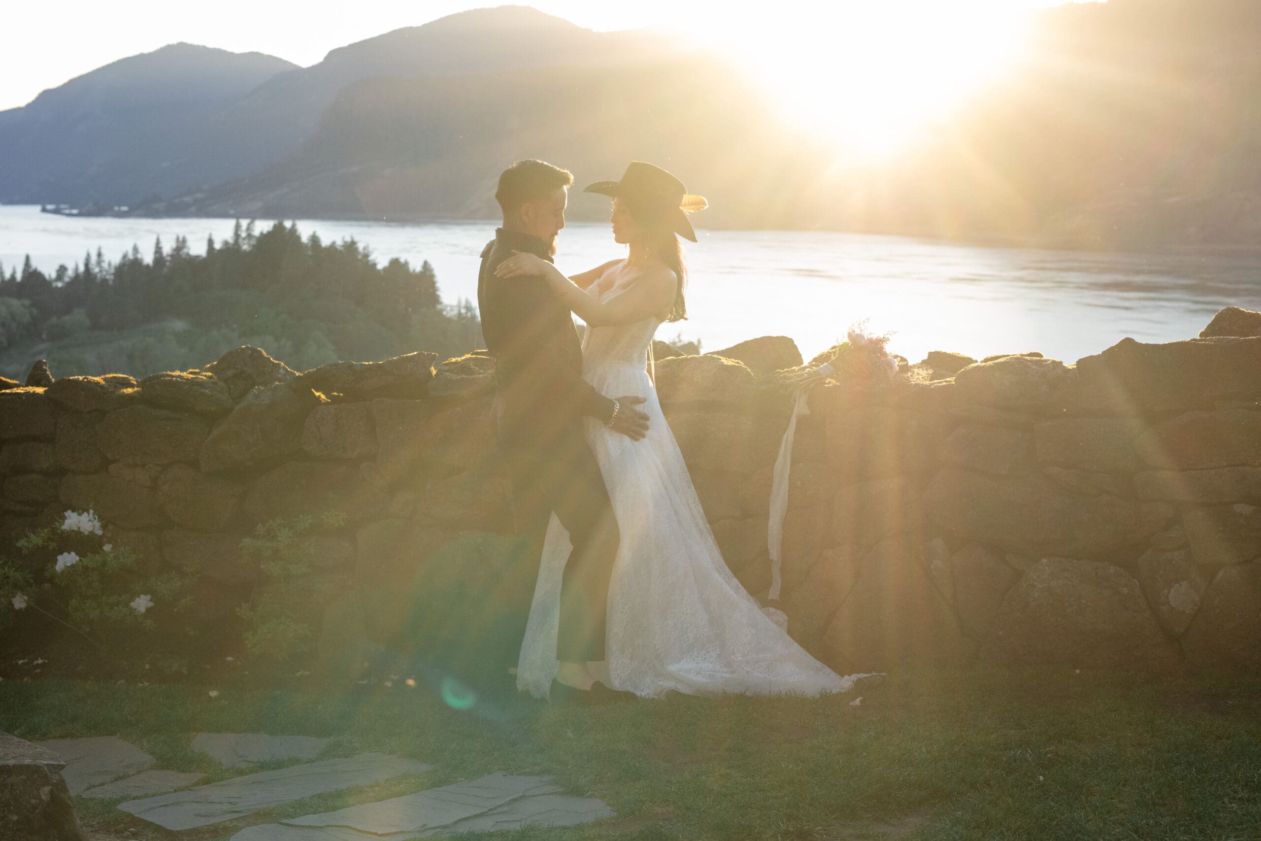 Couple embracing at golden hour with a sweeping mountain and river view, photographed by a Washington wedding photographer focused on light and feeling.
