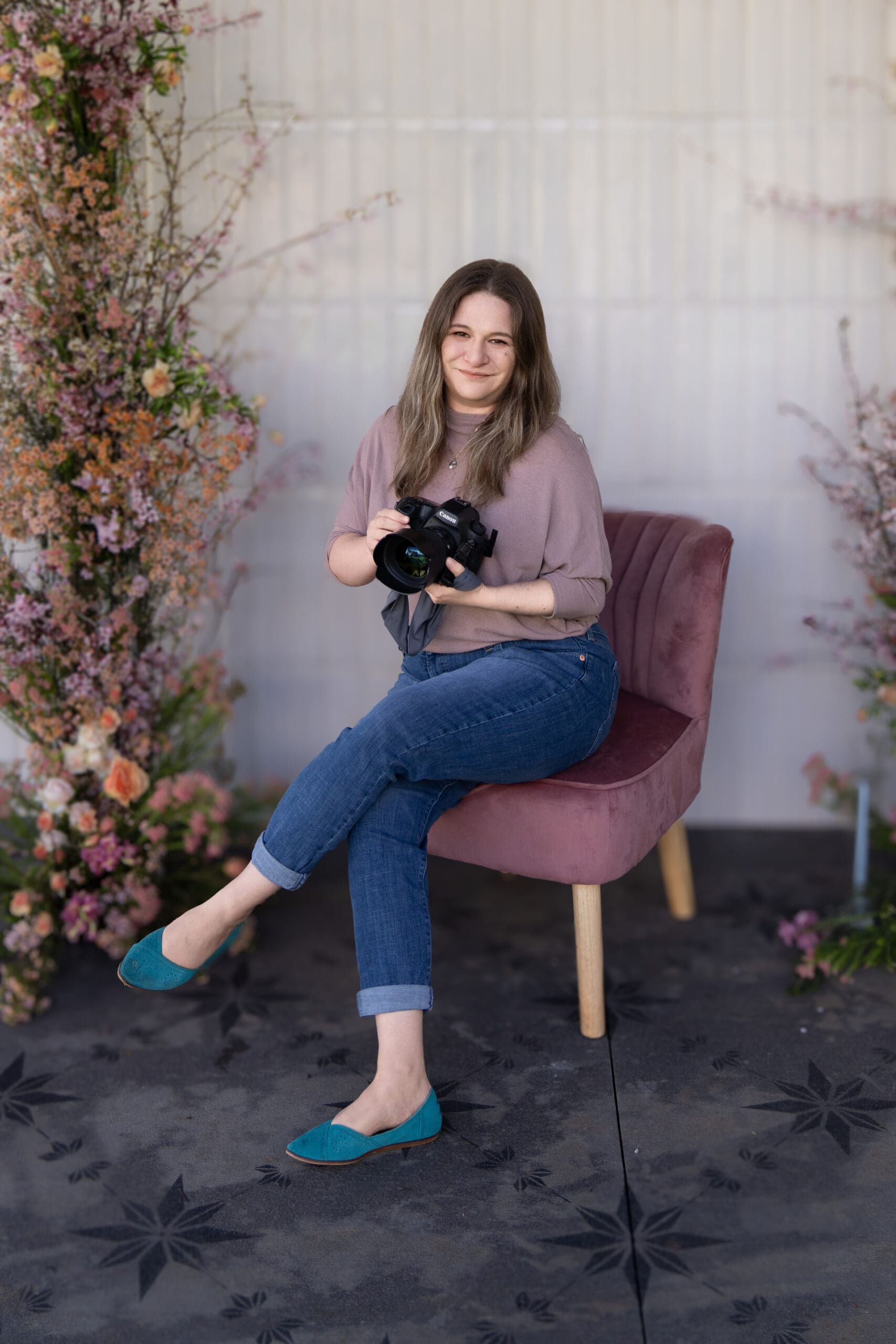 Washington wedding photographer seated with camera in hand, surrounded by floral installations and calm confidence.