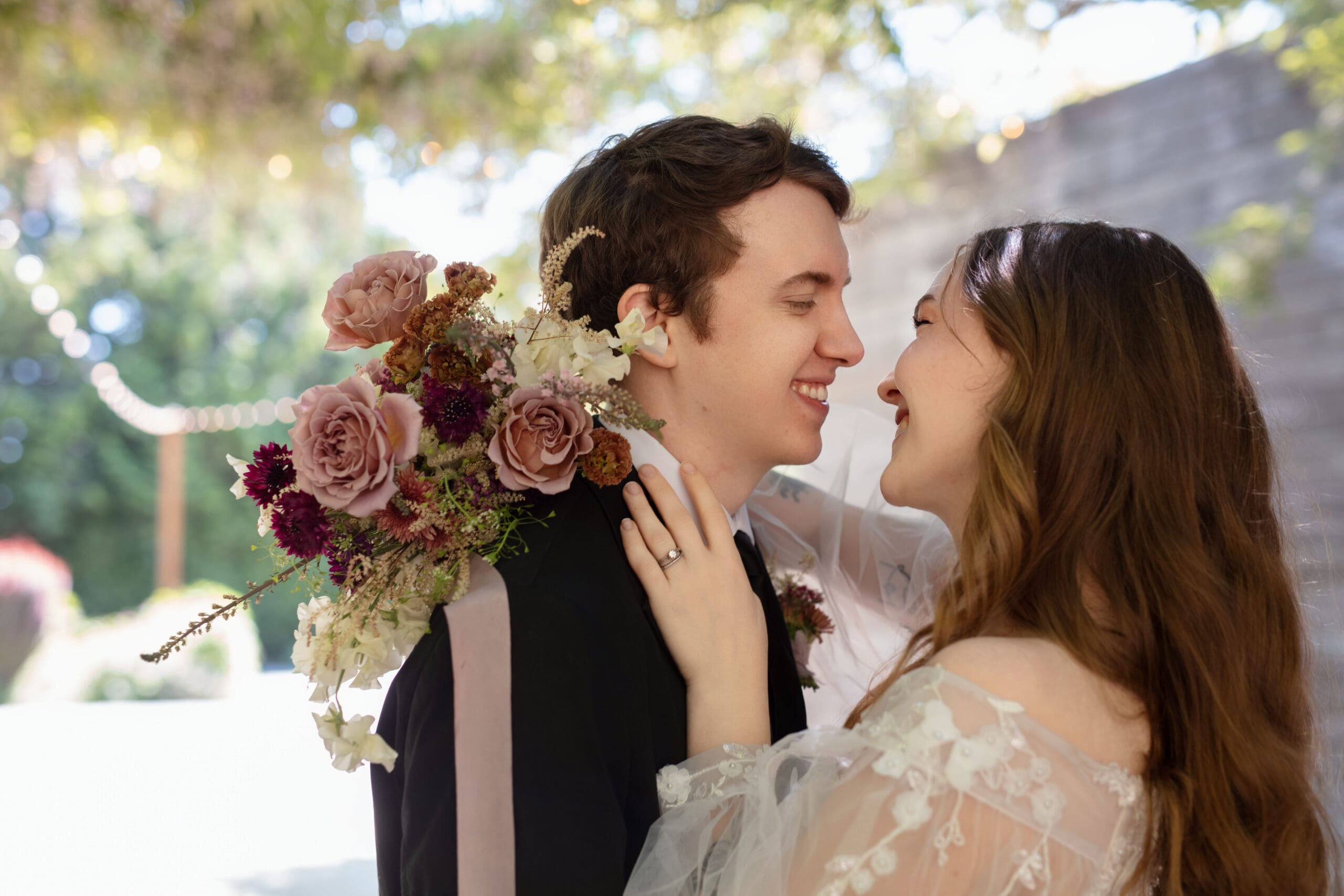 Bride and groom dancing under hanging florals and soft natural light in a private courtyard.