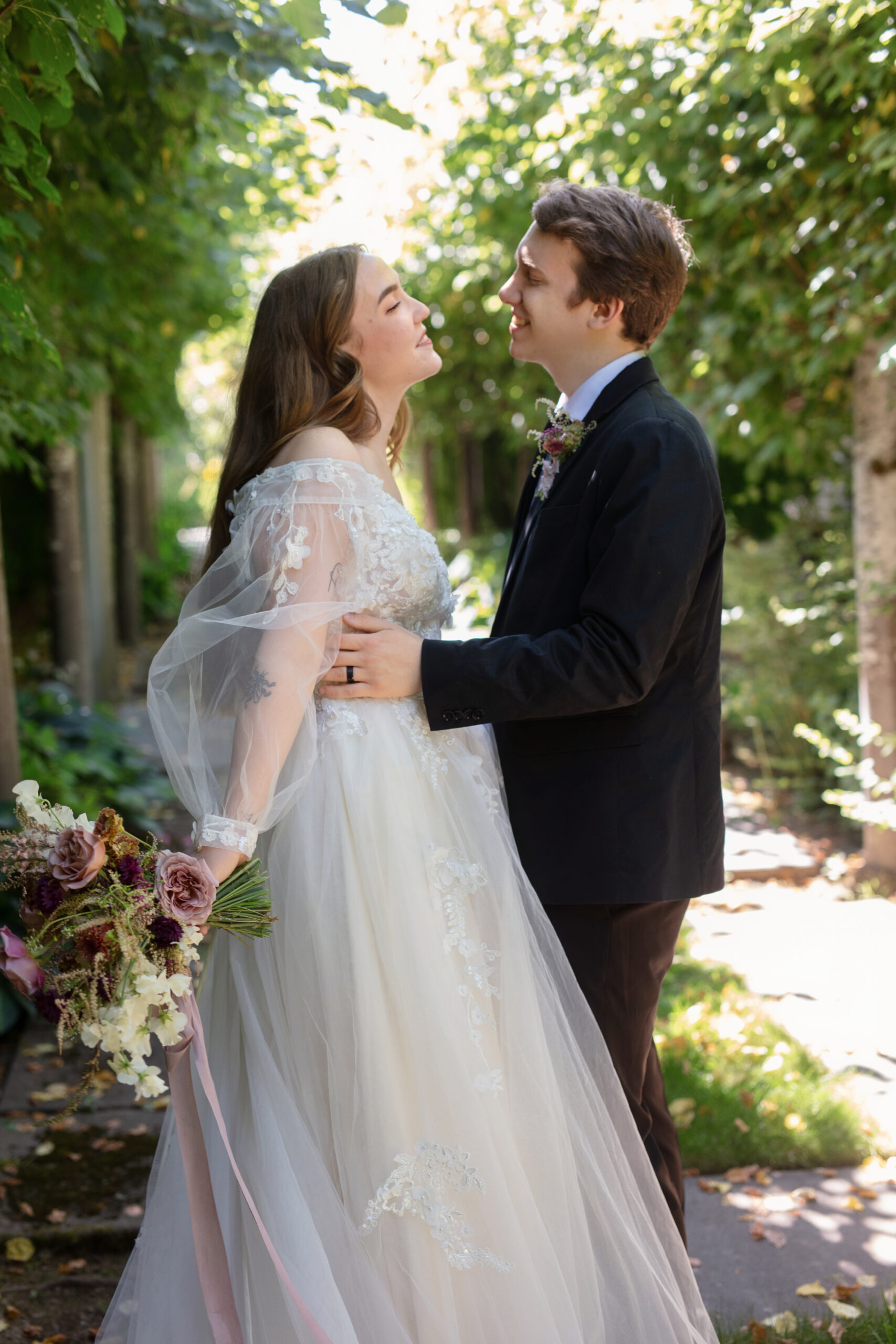 Bride and groom smiling at each other beneath a tree canopy at Briarwood Estate.