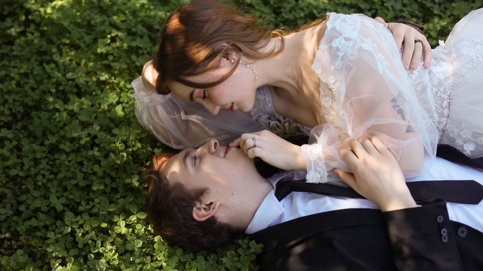 Bride and groom lying in clover patch sharing an intimate moment at Briarwood Estate.

