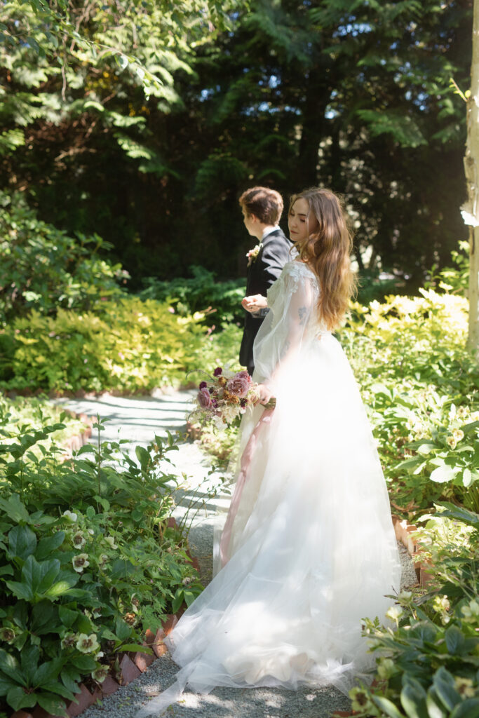 Bride walking along a shaded garden path at Briarwood Estate with groom following behind.