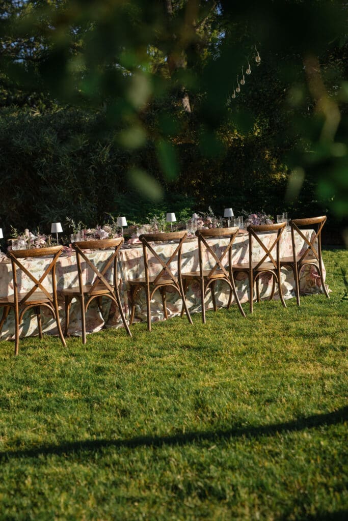 Elegant outdoor reception table setup on the Griffin House lawn, styled with floral linens and wood chairs.