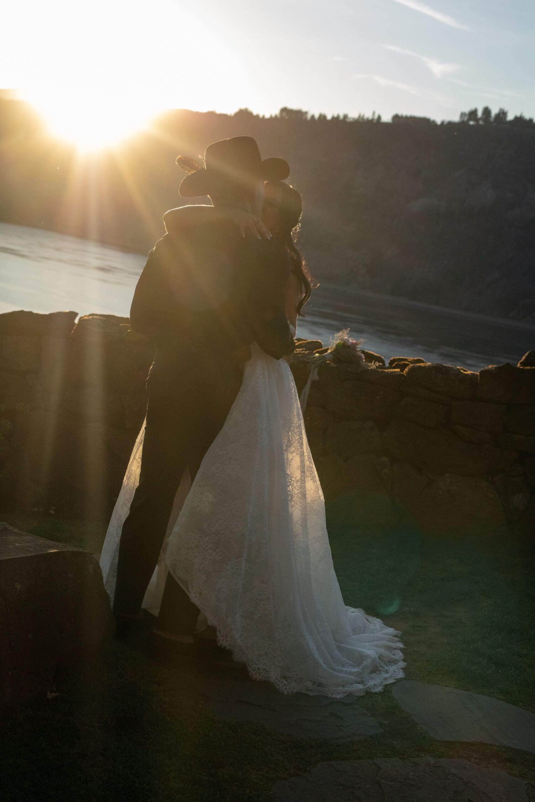 Bride and groom embrace at sunset beside the iconic stone wall at their Griffin House wedding.