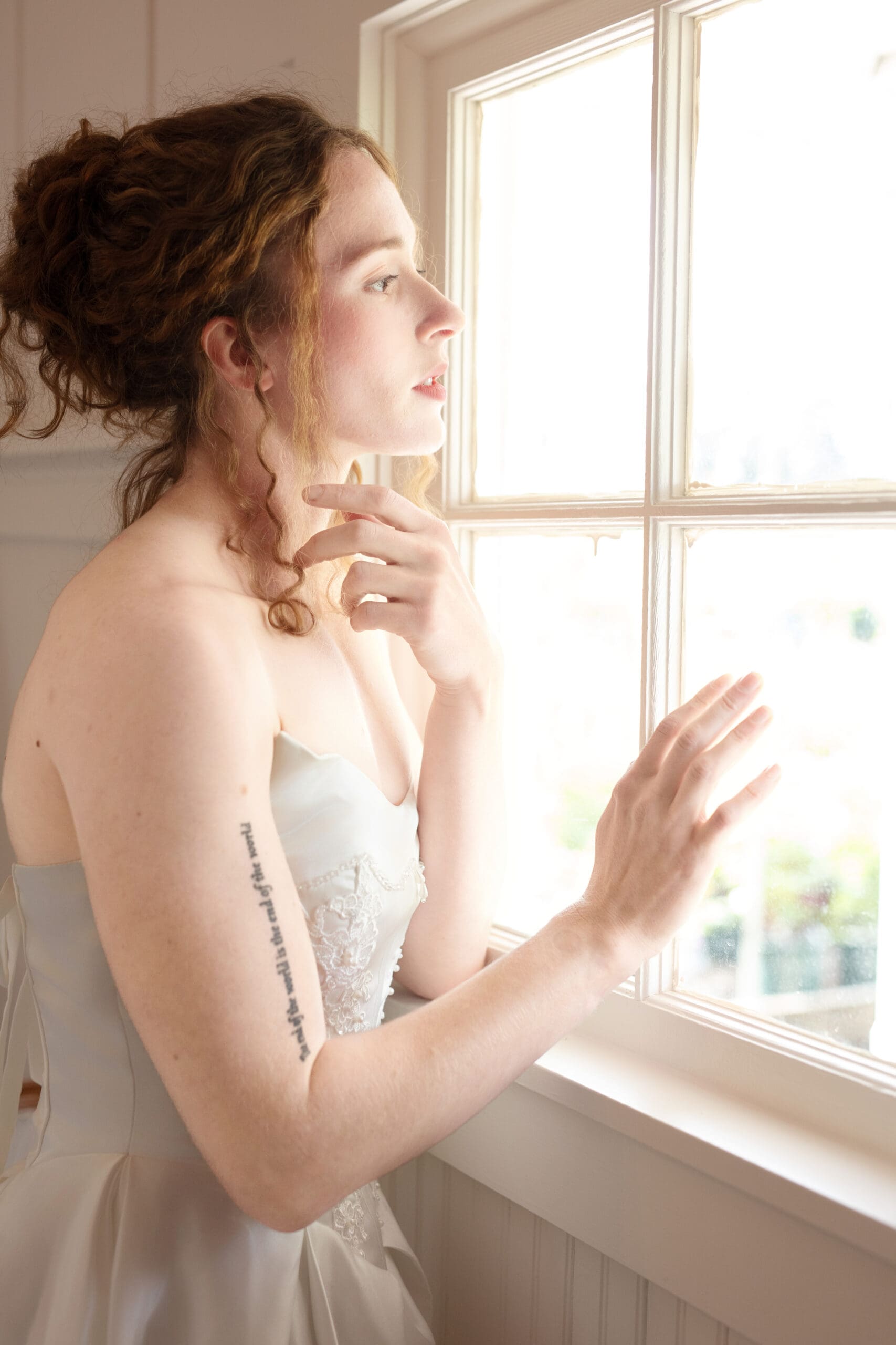 Bride looks thoughtfully out the window of the bridal suite at this Washington wedding venue.