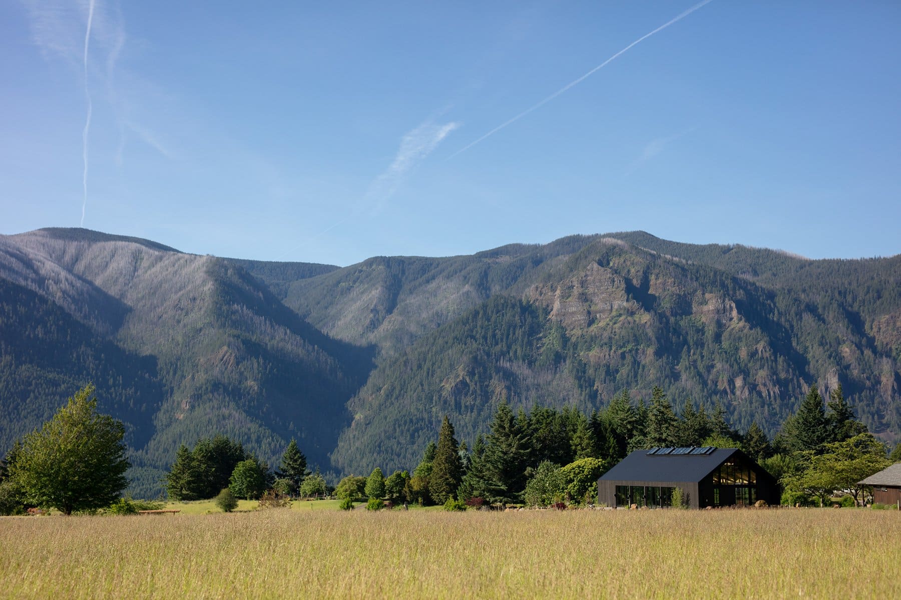 Wind mountain ranch venue seen from afar with its black barn nestled beneath the dramatic Columbia Gorge mountain range.