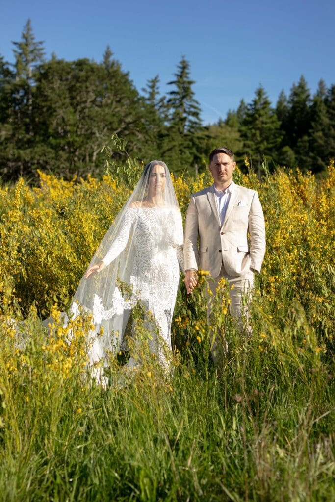 Bride and groom standing in a wildflower field surrounded by golden blooms during their Columbia Gorge wedding