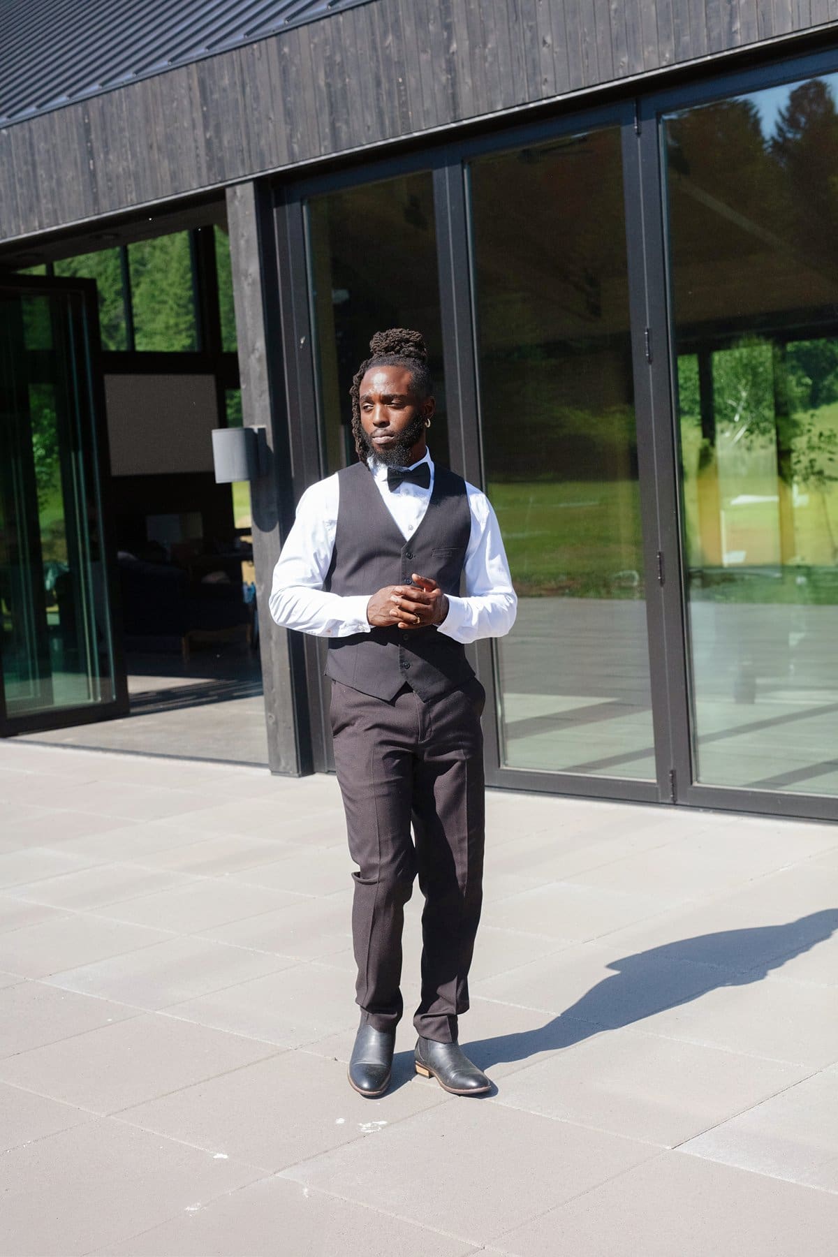 Groom stands confidently in front of the black modern reception space at wind mountain ranch venue.
