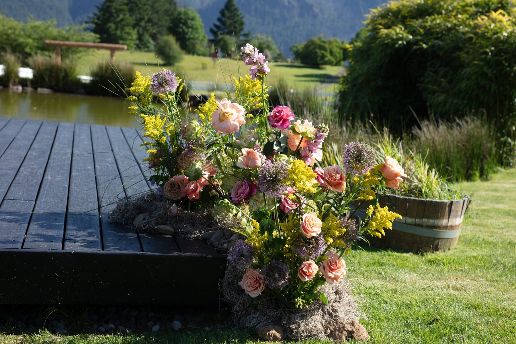 Lush and colorful floral arrangement set beside the dock and pond at wind mountain ranch venue.