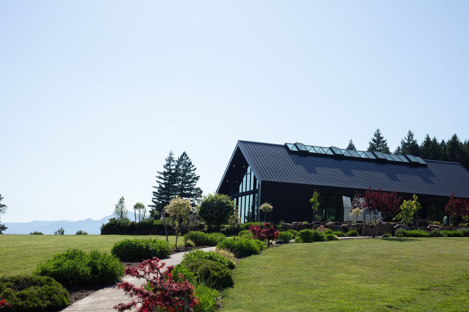 Wide view of wind mountain ranch venue’s sleek black reception building surrounded by landscaped gardens and open fields.
