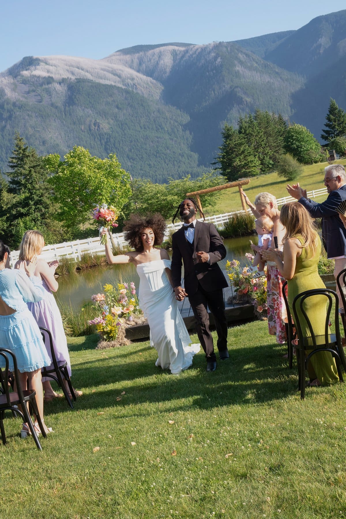 The bride and groom walk back down the aisle together, guests cheering around them at Wind Mountain Ranch venue.
