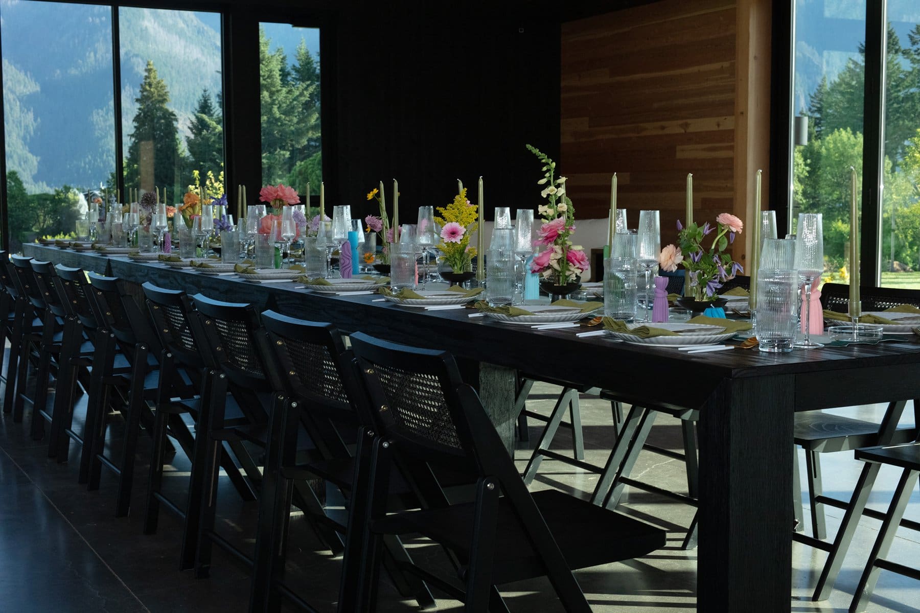 Reception table setup with colorful flowers and tapered candles inside wind mountain ranch venue.