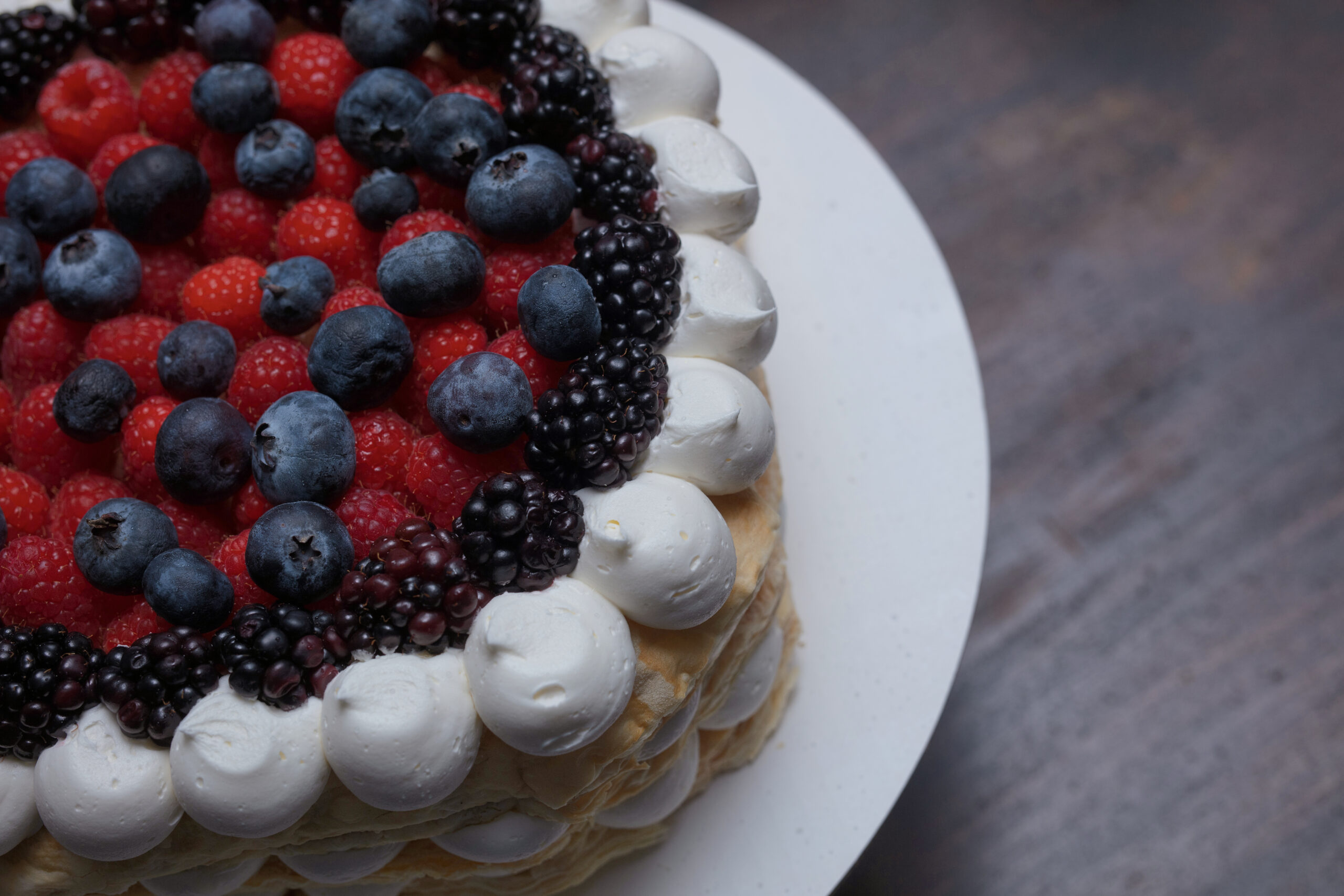 Layered cake decorated with whipped cream and fresh berries – beautiful dessert styling ideas for weddings.