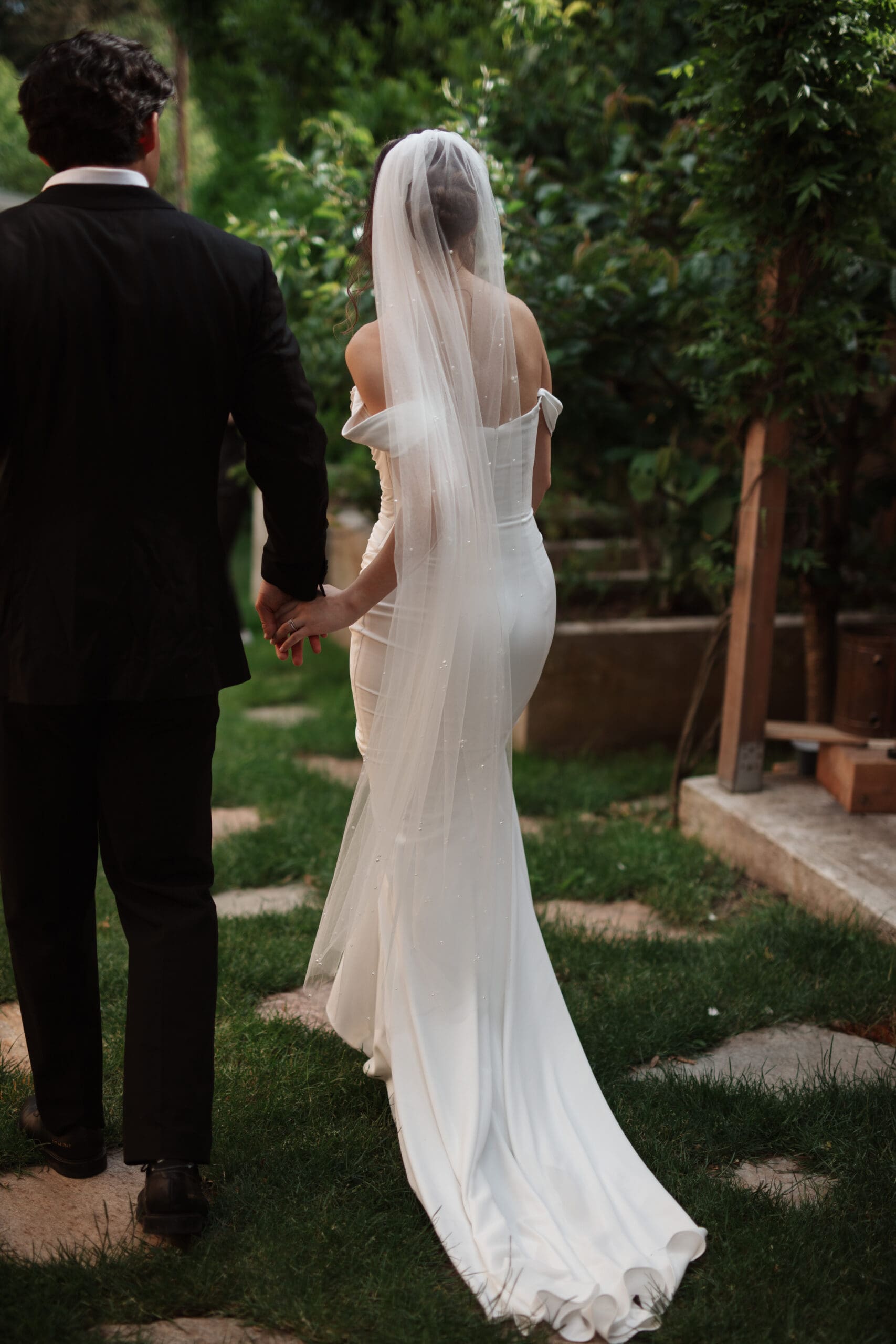 Couple walks hand-in-hand through a garden path, backlit by soft golden hour – romantic send-off ideas for weddings.