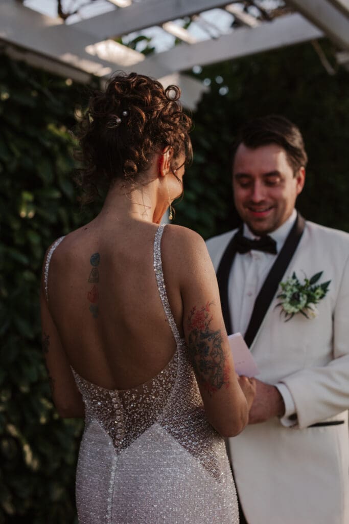 Bride reads her vows while groom smiles lovingly – heartfelt vow exchange ideas for weddings.