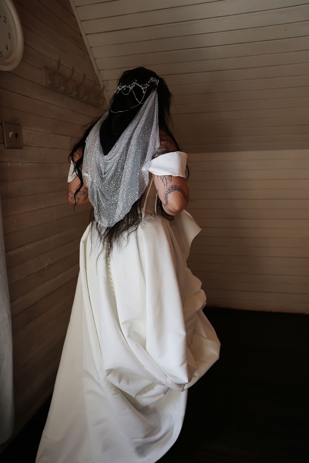 Bride walking through the bridal suite at Cape Horn Estate, revealing the back of her satin gown and sparkling veil.