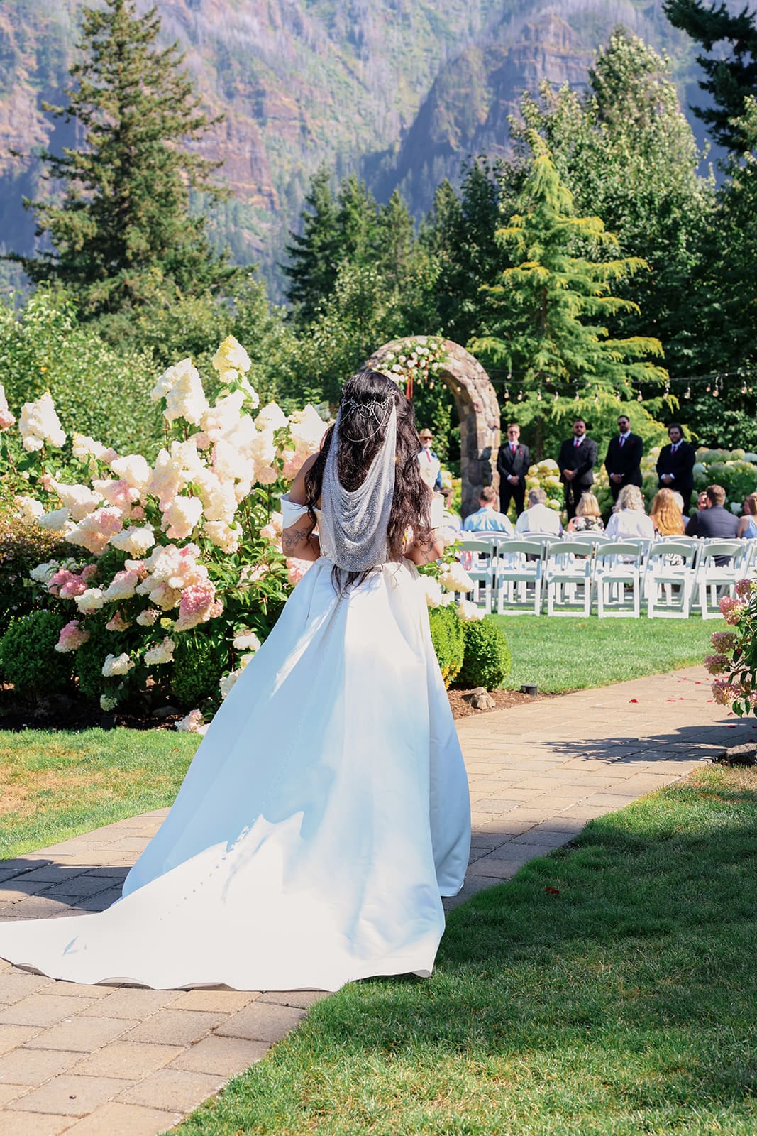 Bride making her entrance at Cape Horn Estate, walking the garden path toward a floral ceremony arch in the Columbia Gorge.