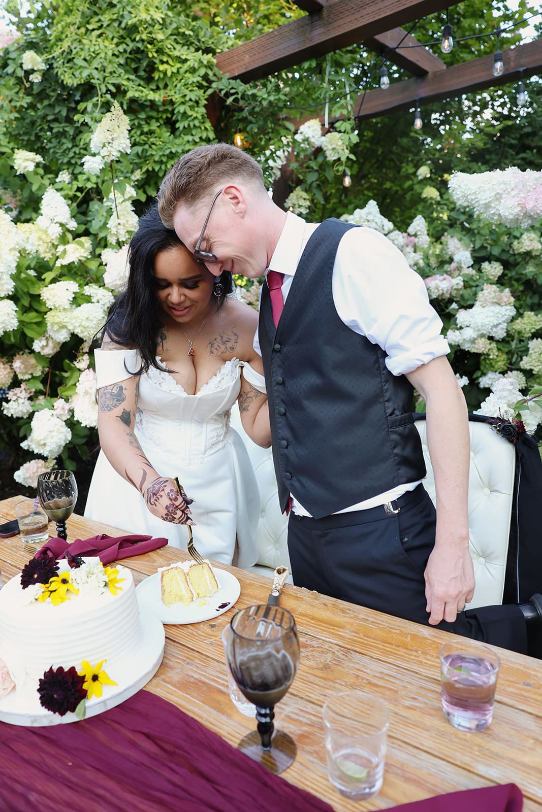 Couple cutting their cake at Cape Horn Estate, surrounded by lush floral landscaping and romantic outdoor reception decor.