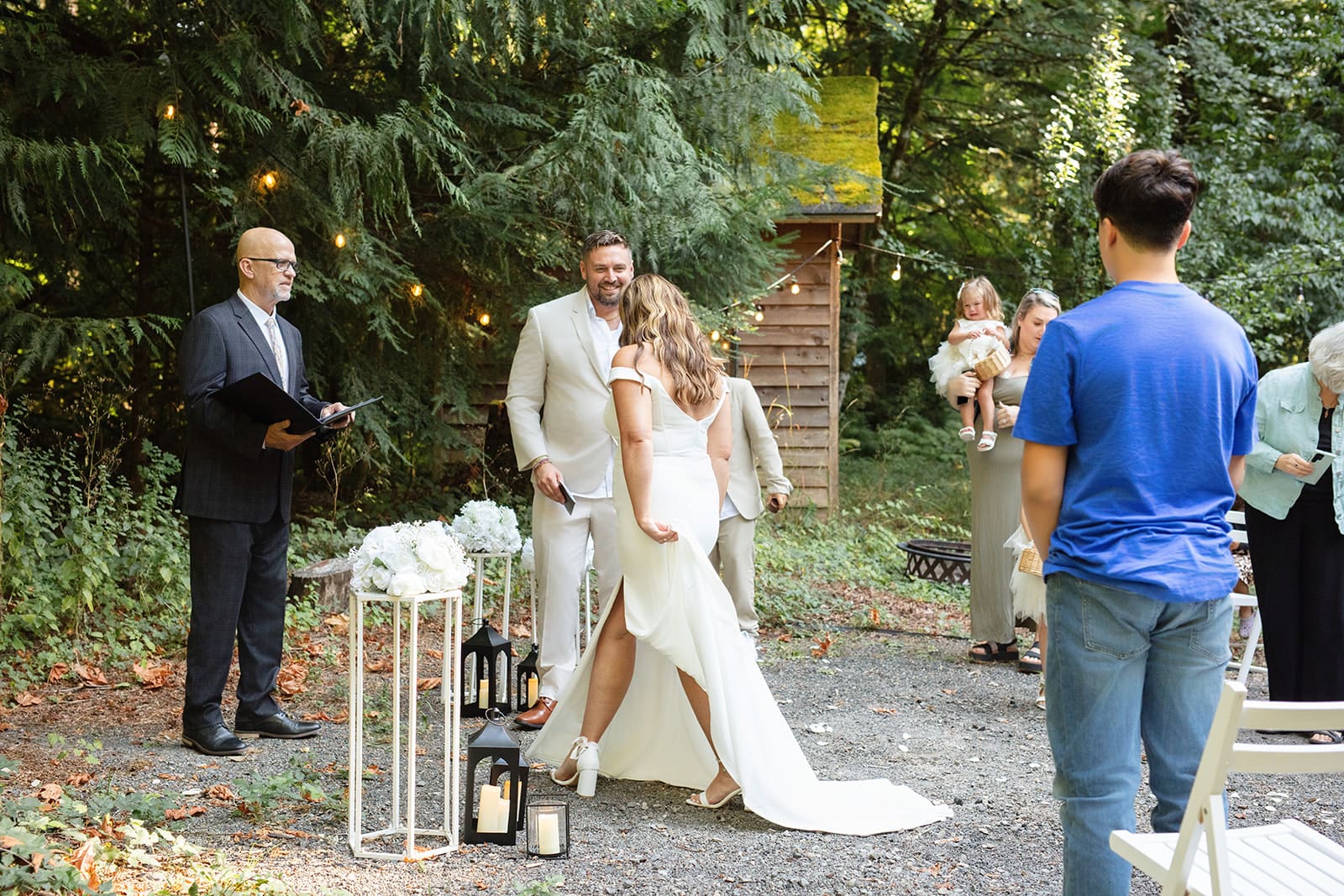 The bride walks toward her groom, smiling as their officiant waits nearby — a relaxed and joyful airbnb weddings moment.