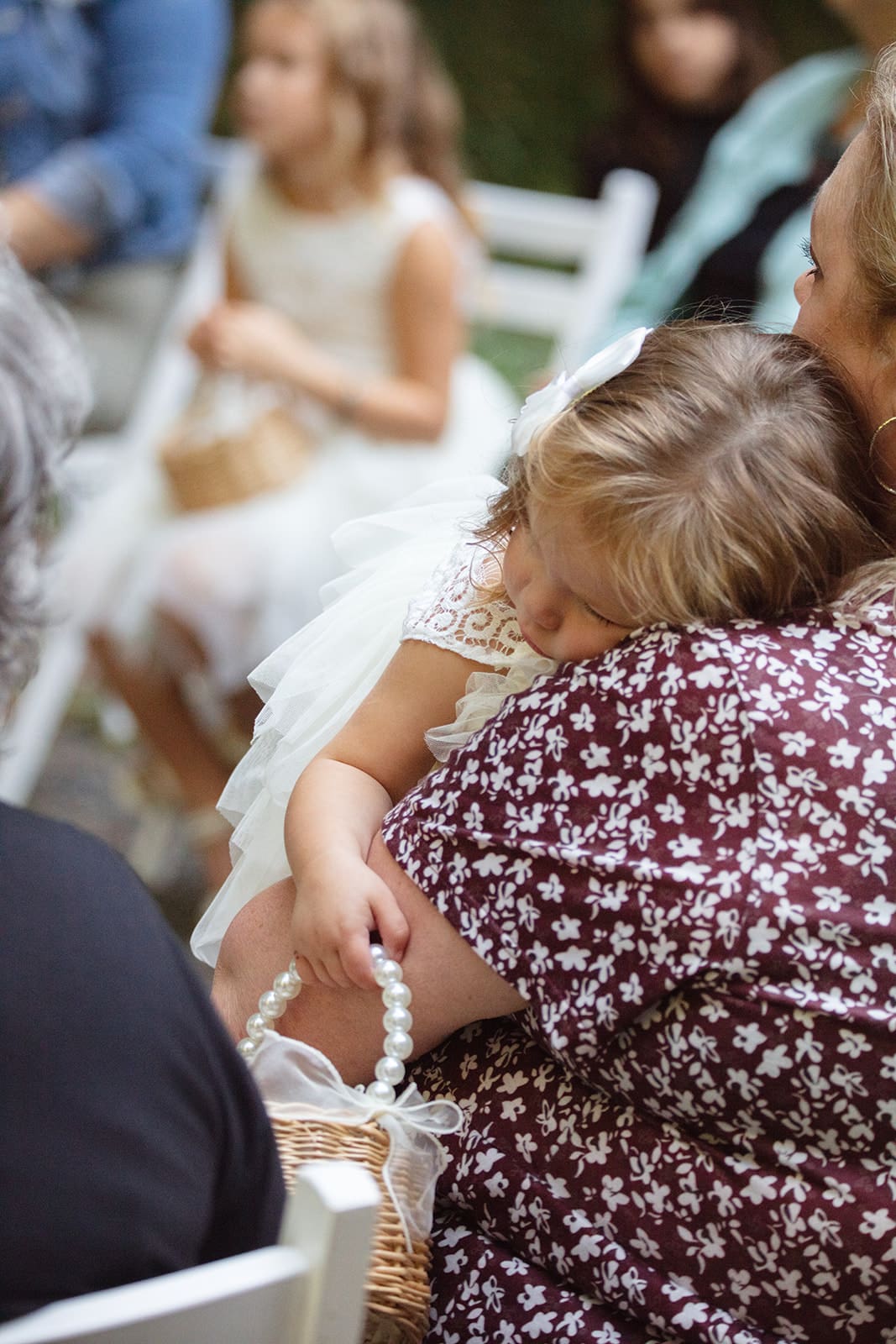 A young flower girl with blonde curls looks back over her shoulder and smiles sweetly during the ceremony — airbnb weddings often capture these candid family moments.
