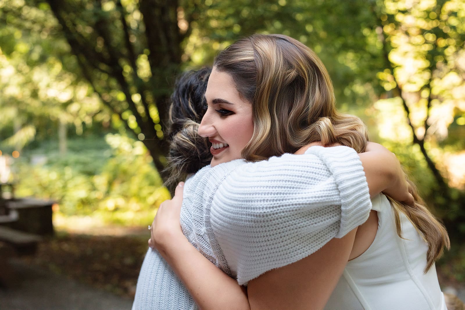 A heartfelt hug between the bride and a close friend beneath the forest canopy — an authentic airbnb weddings moment.