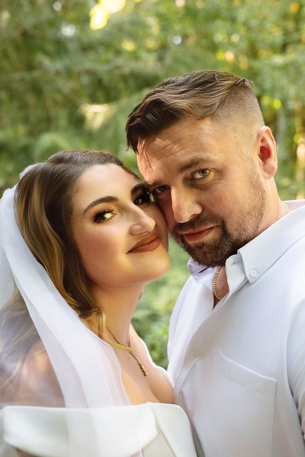Close-up portrait of the couple cheek to cheek, surrounded by warm, golden light and lush greenery — perfect for airbnb weddings inspiration.