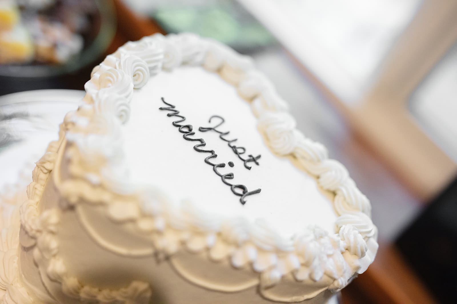 A small white cake with “Just Married” written in black frosting, simple and heartfelt.