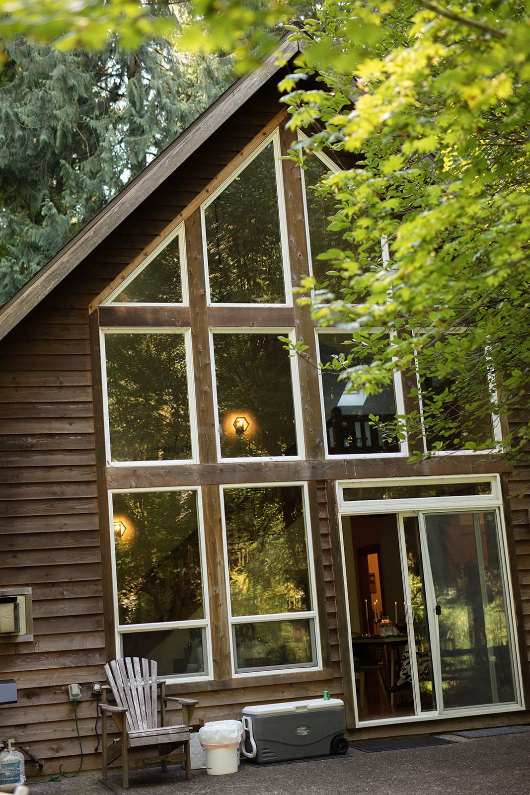 A-frame cabin with tall windows reflecting forest light, setting the scene for an intimate airbnb wedding celebration.