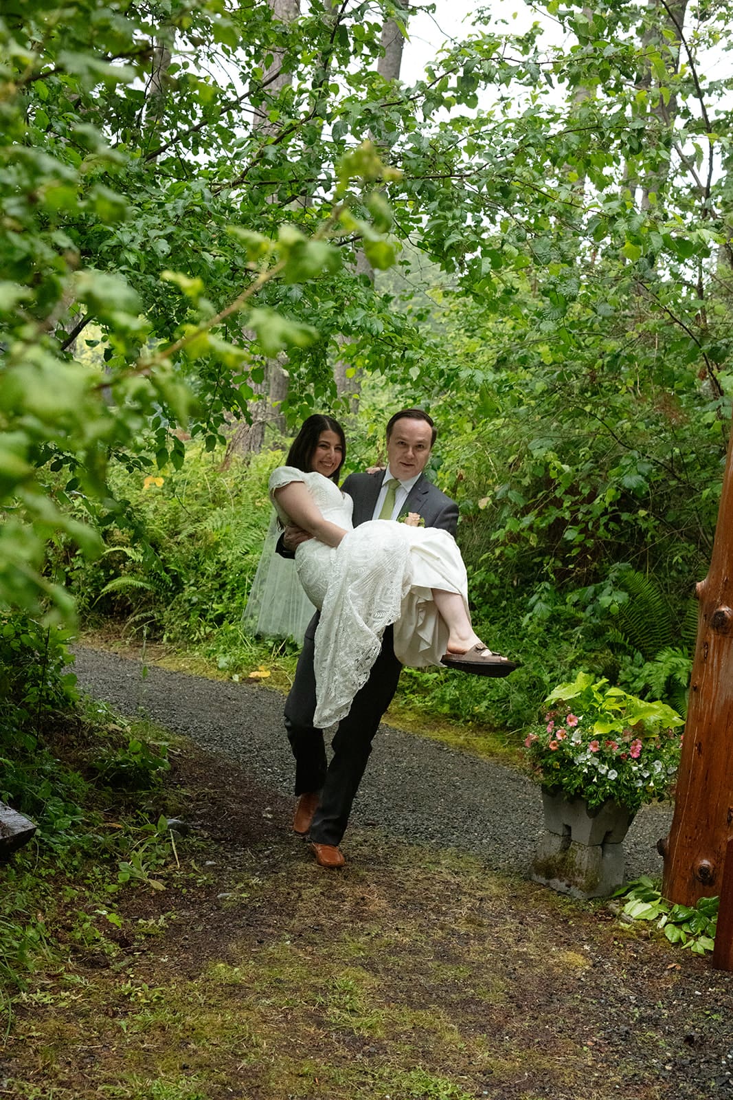 Groom carrying his bride through a wooded garden trail during their romantic wedding in Washington state.