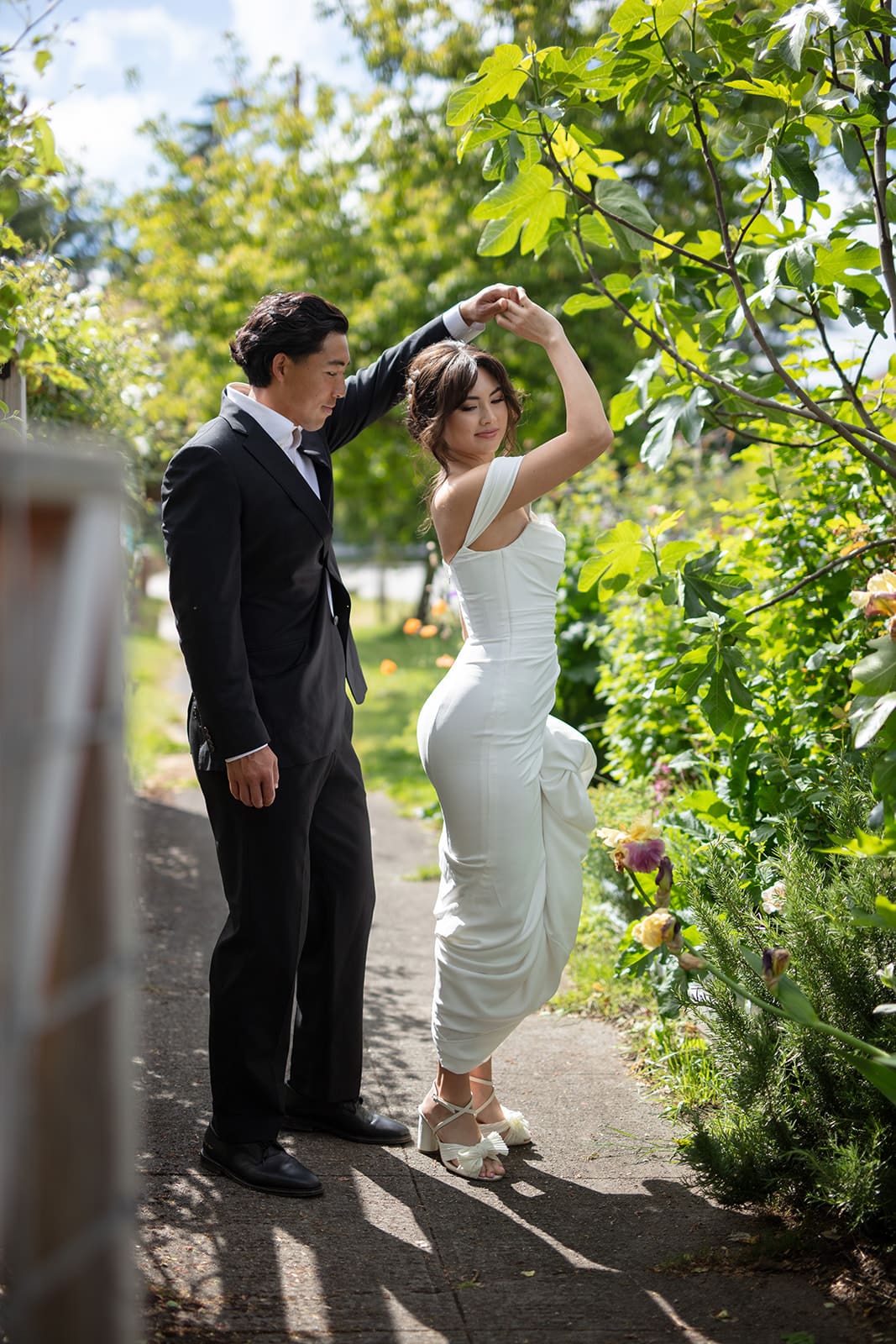 Whimsical twirl between bride and groom under the trees at their wedding in Washington state.