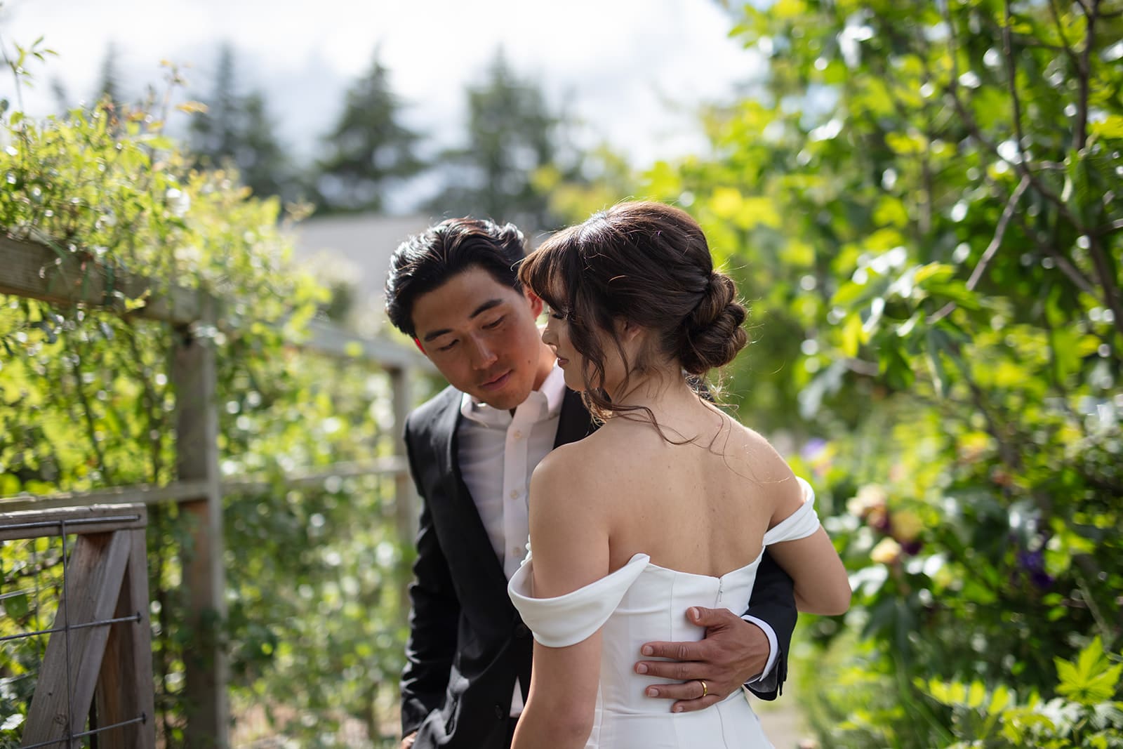 Romantic moment between bride and groom during their wedding in Washington state, surrounded by lush greenery.