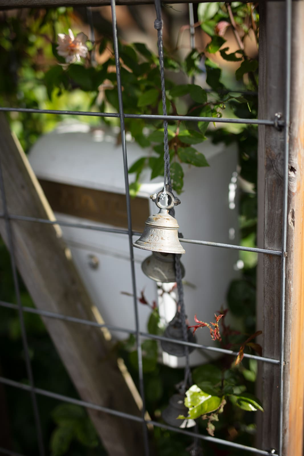 Close-up of a rustic wedding detail: a small bell tied to a garden fence near a white mailbox, adding charm to a wedding in Washington state.