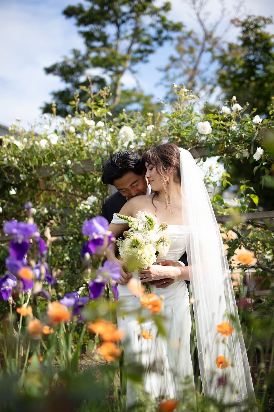 A tender moment between bride and groom surrounded by blooming flowers during their wedding in Washington state.