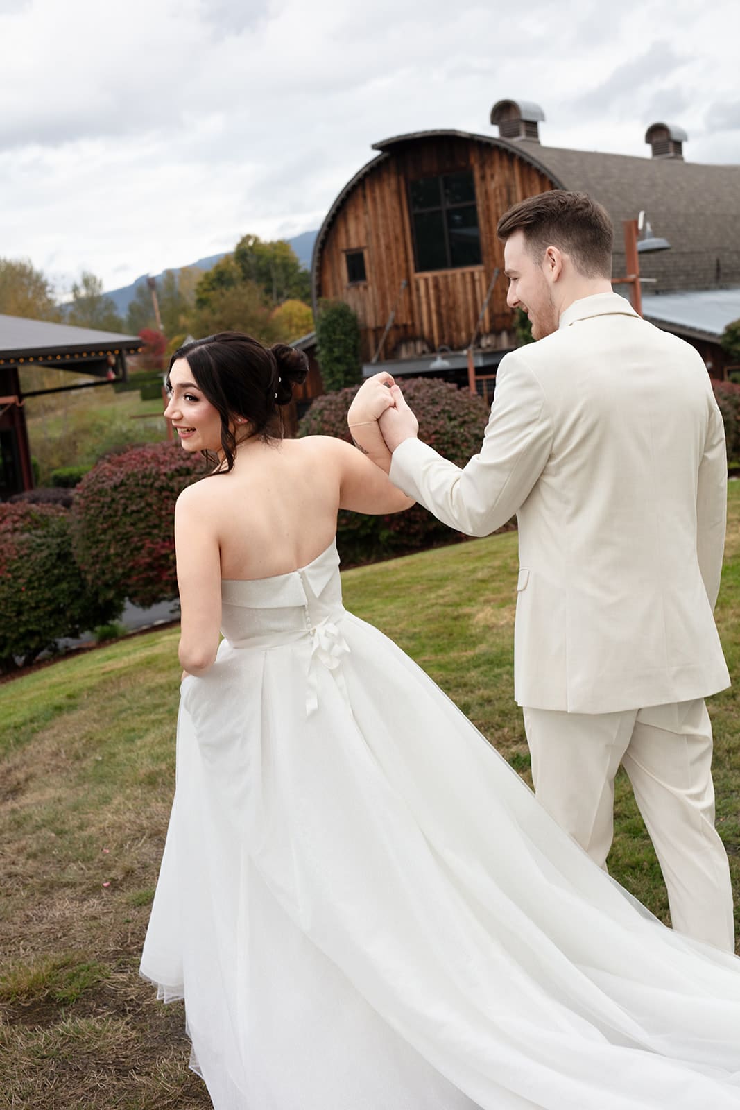 Bride glancing back with a smile while walking hand-in-hand with groom on their wedding day.