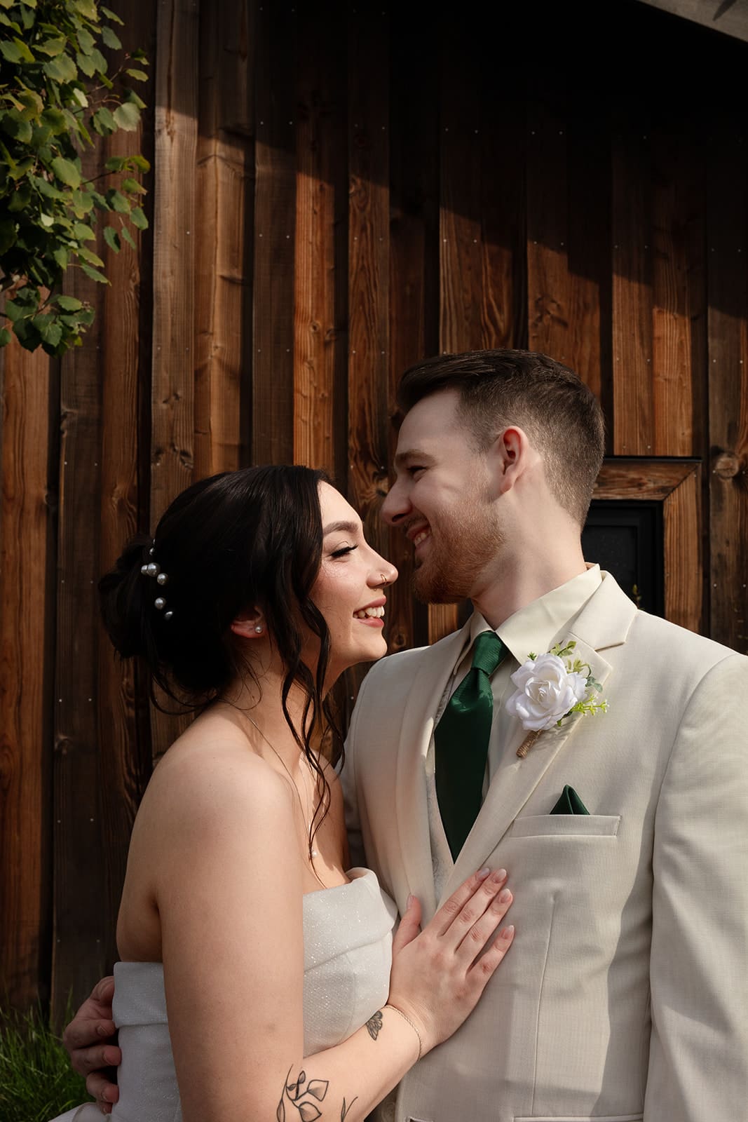 A candid moment of newlyweds laughing together outside a rustic barn venue.