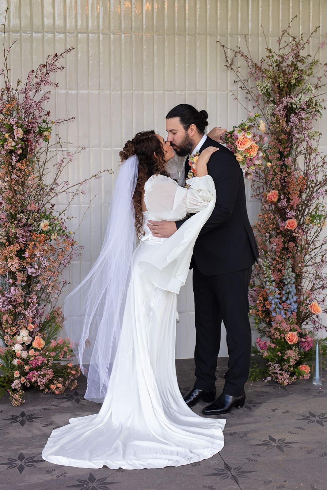 Romantic kiss between bride and groom at their colorful wedding altar in Washington state.