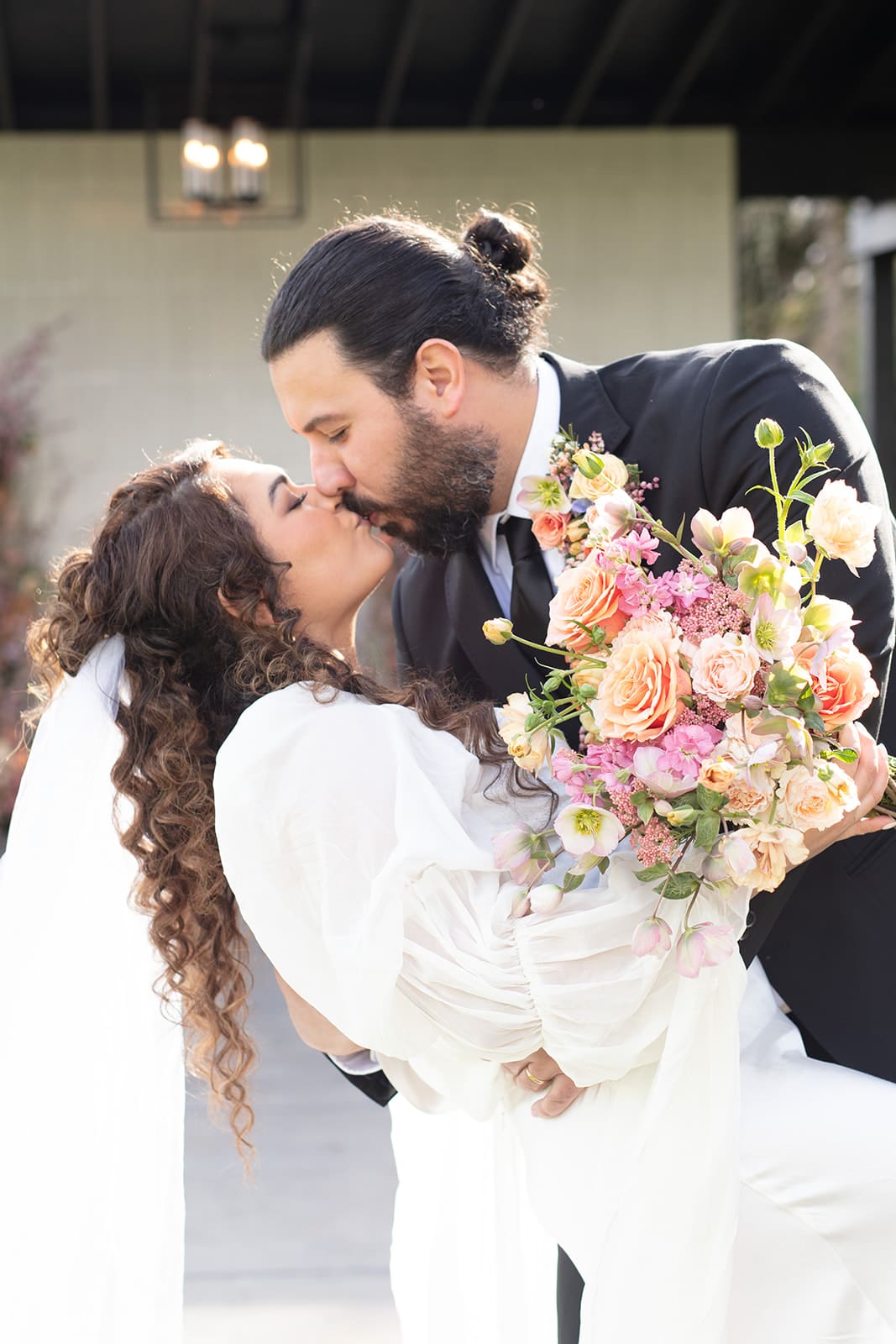 A romantic dip kiss between bride and groom, celebrating their wedding in Washington state with a spring bouquet.