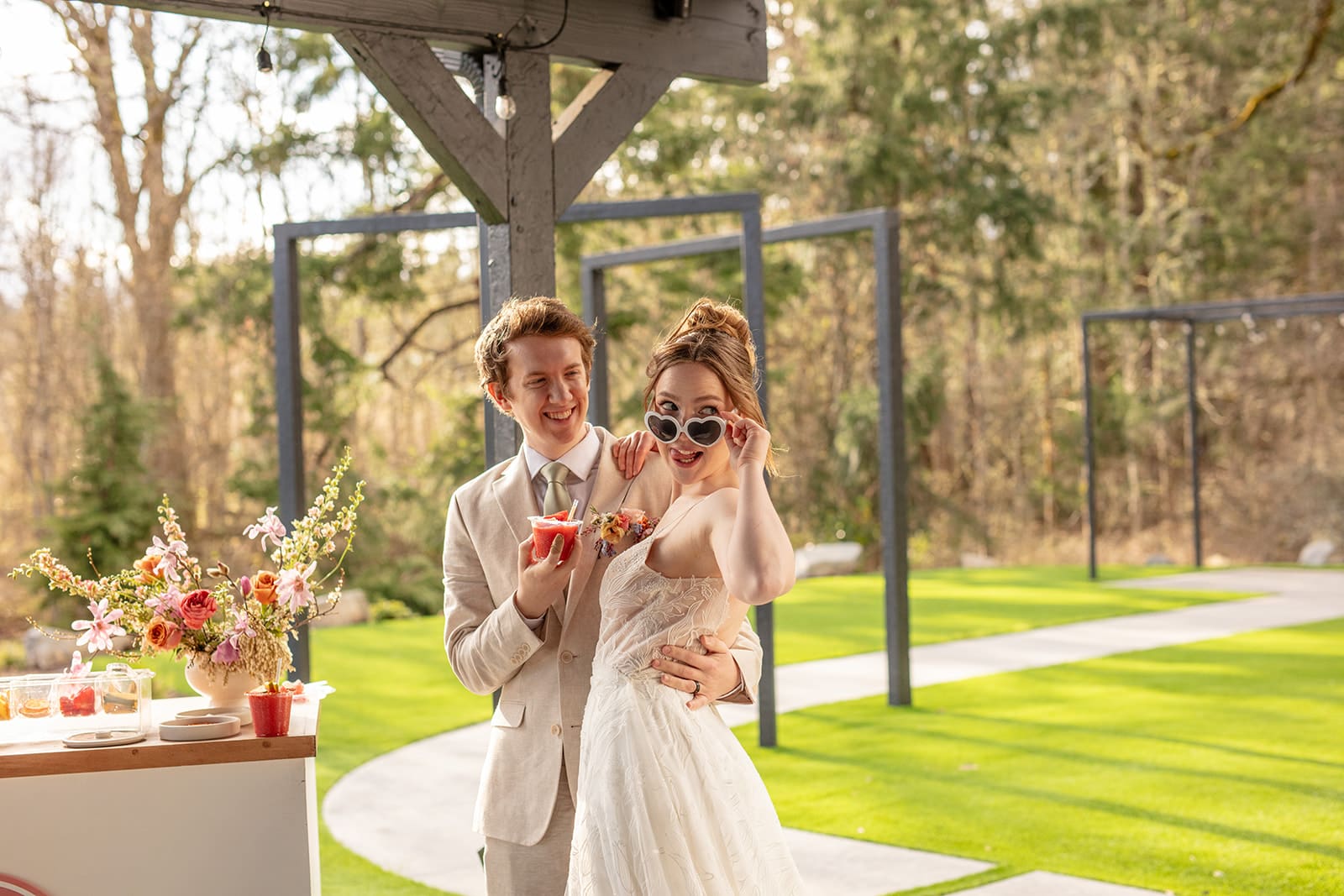Fun and flirty wedding reception moment with bride in heart-shaped sunglasses and fruity cocktails.