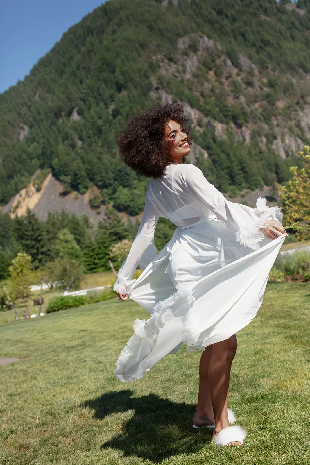Carefree bride twirling on the lawn with Washington mountains as the backdrop before her wedding in Washington state.